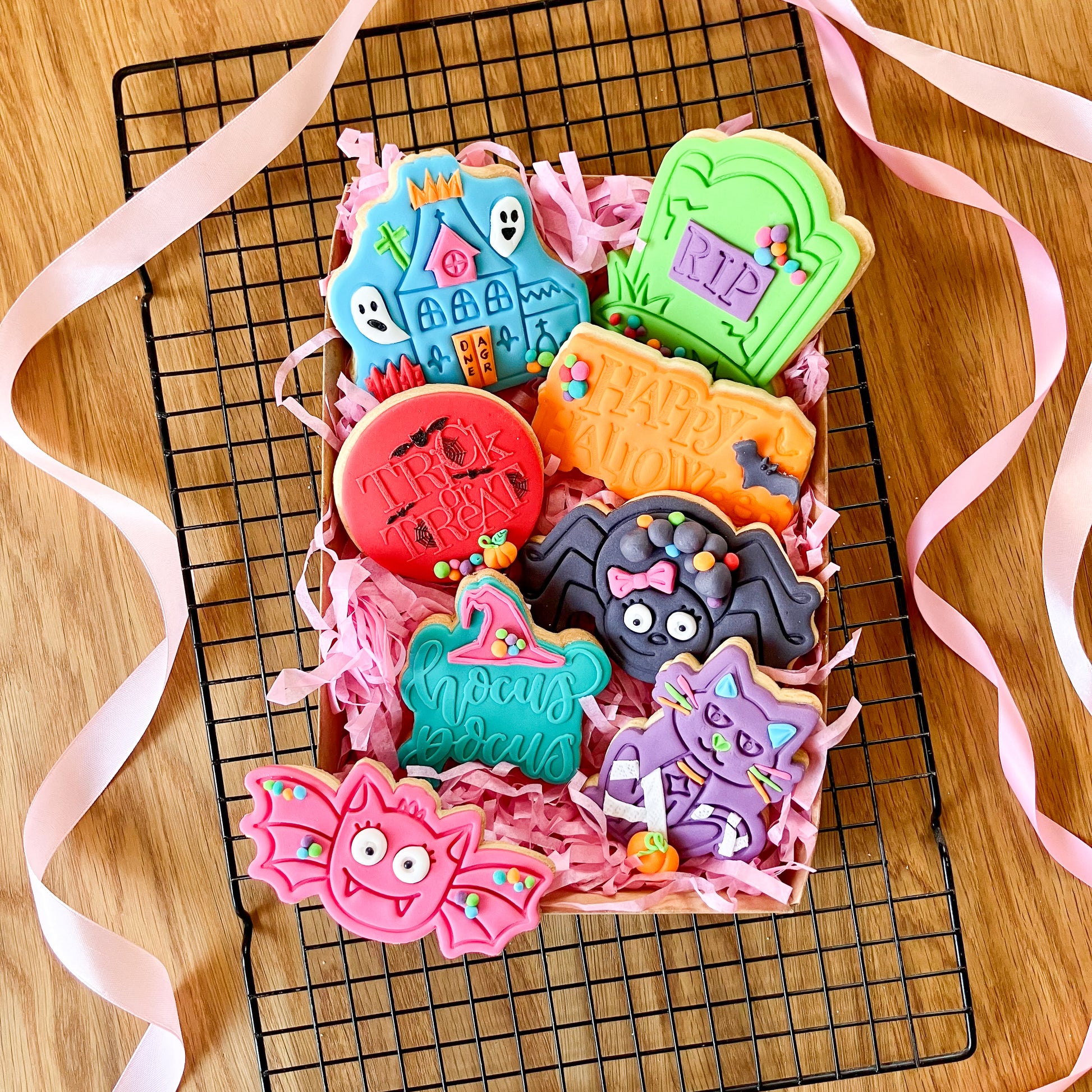 Colorful Halloween-themed cookies on a cooling rack with decorative ribbons.