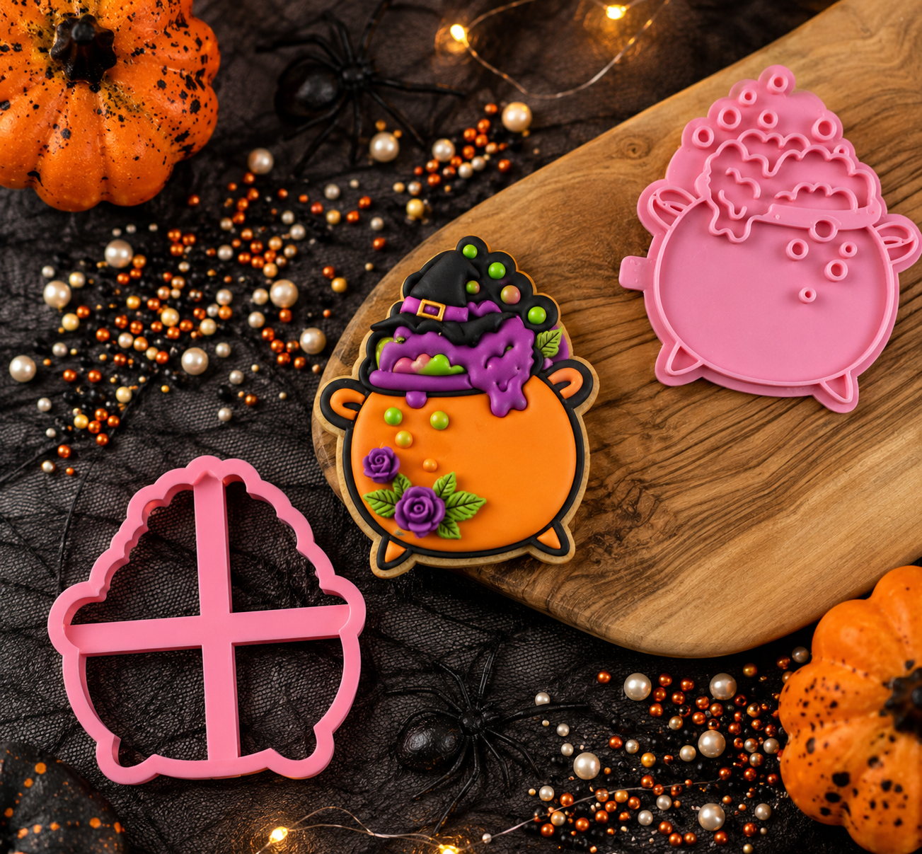 Halloween-themed cookie cutters on a wooden board with pumpkins and decorative lights.