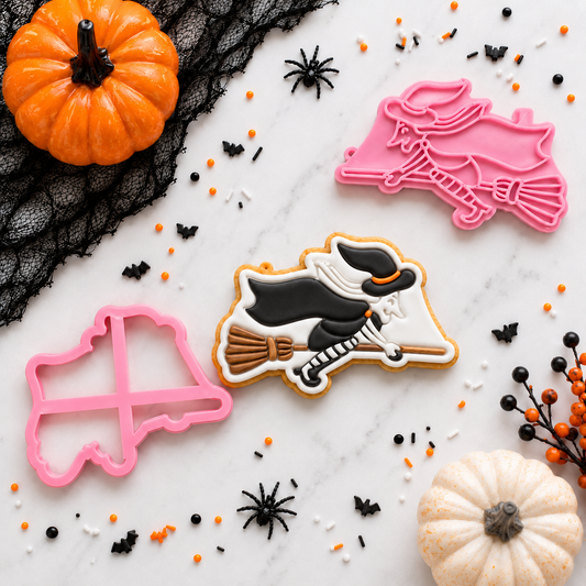 Halloween-themed cookie cutters and decorated cookies on a marble surface with pumpkins and spider webs.