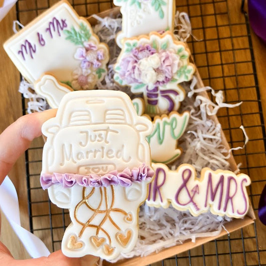 Decorative cookies with 'Just Married' and 'Mr & Mrs' text on a wooden board.