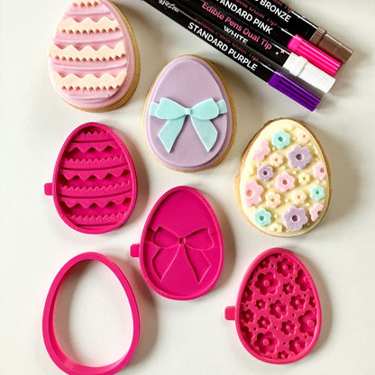 Easter egg-shaped cookies with decorative tools on a white background
